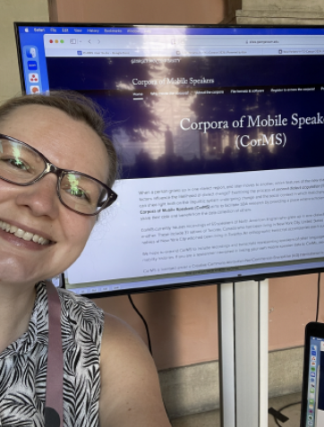 Prof. Jen Nycz taking a selfie in front of a monitor with the CorMS website displayed. 