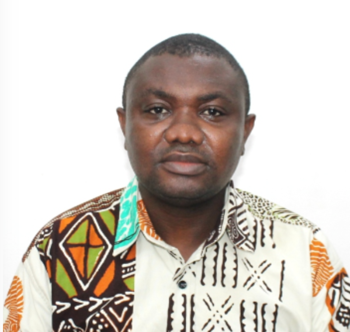 Prof. Michael Obiri-Yeboah is a Black man with a buzz cut. He is wearing a colorful button-down shirt with an African print. 