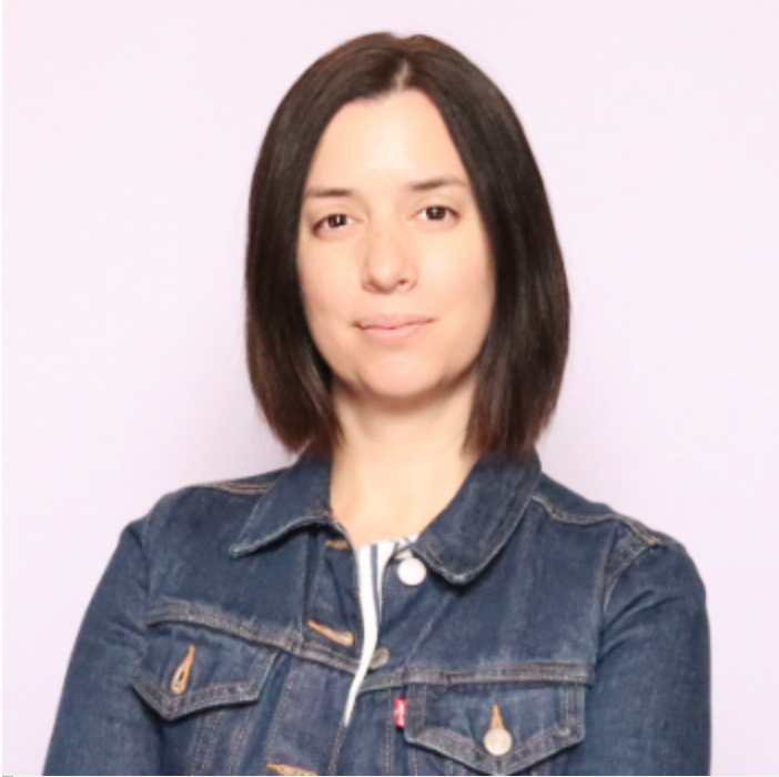 Portrait of Prof. Nadja Tadić in a denim jacket, neutral light background, facing camera with a slight smile